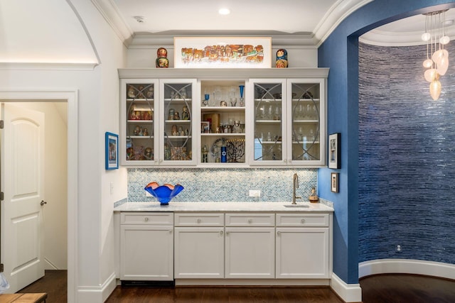 14 Lyonsgate Rd, Bexley, OH 43209 - indoor wet bar featuring ornamental molding, dark wood-type flooring, backsplash, arched walkways, and baseboards