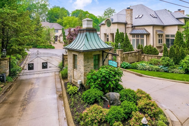 14 Lyonsgate Rd, Bexley, OH 43209 - view of front of home featuring a standing seam roof, a gate, stone siding, a chimney, and metal roof