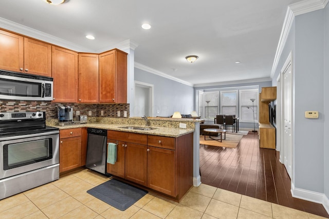 925 Ingleside Ave Unit 213, Columbus, OH 43215 - kitchen with appliances with stainless steel finishes, a peninsula, a sink, crown molding, and brown cabinetry