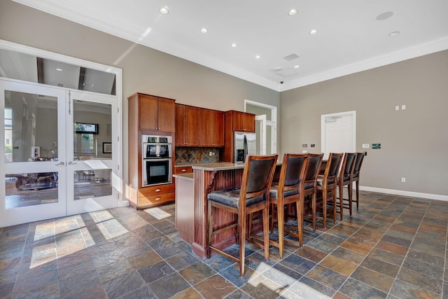 925 Ingleside Ave Unit 213, Columbus, OH 43215 - kitchen with stainless steel appliances, stone tile flooring, ornamental molding, baseboards, and a kitchen bar