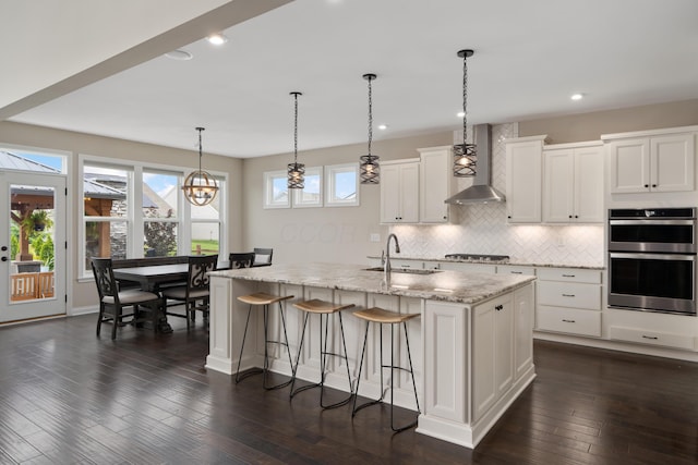 3669 Audubon Ave, Hilliard, OH 43026 - kitchen with wall chimney range hood, stainless steel appliances, a sink, a kitchen breakfast bar, and tasteful backsplash