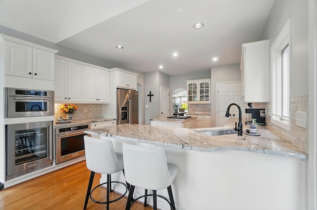 9146 Shawnee Trl, Powell, OH 43065 - kitchen featuring high end fridge, a sink, a peninsula, tasteful backsplash, and recessed lighting