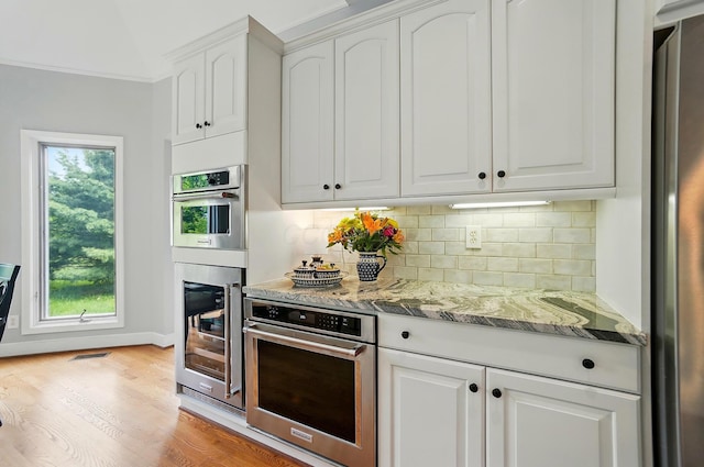 9146 Shawnee Trl, Powell, OH 43065 - kitchen featuring appliances with stainless steel finishes, backsplash, light stone countertops, white cabinetry, and light wood-style floors