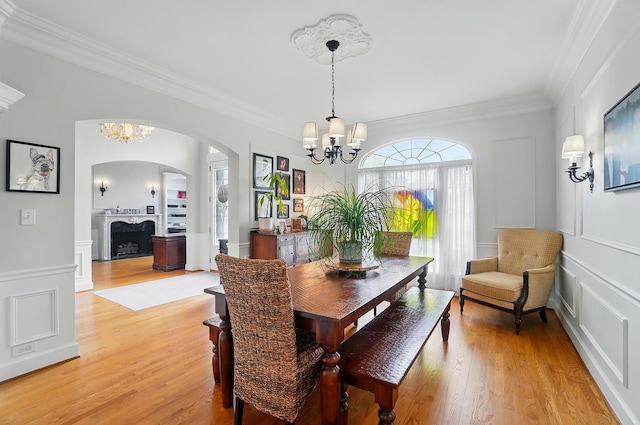 9146 Shawnee Trl, Powell, OH 43065 - dining space with a chandelier, arched walkways, ornamental molding, light wood-type flooring, and a decorative wall