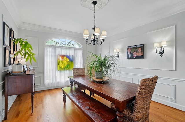 9146 Shawnee Trl, Powell, OH 43065 - dining area with a decorative wall, a chandelier, crown molding, light wood finished floors, and wainscoting