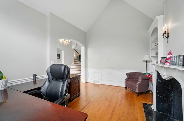 9146 Shawnee Trl, Powell, OH 43065 - office space featuring a fireplace, wood finished floors, a wainscoted wall, high vaulted ceiling, and arched walkways