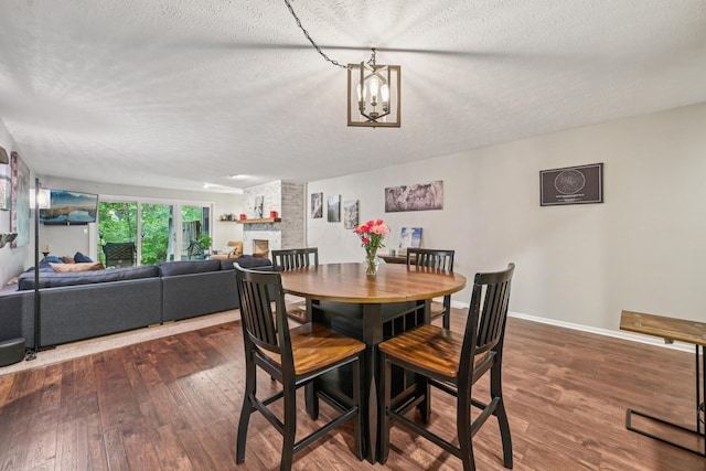 3137 Griggsview Ct Unit 3137, Columbus, OH 43221 - dining area featuring hardwood / wood-style floors, a textured ceiling, a fireplace, a chandelier, and baseboards