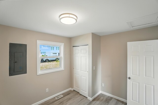 4881 Decker Ave NE, Thornville, OH 43076 - unfurnished bedroom with electric panel, light wood-style flooring, baseboards, a closet, and attic access