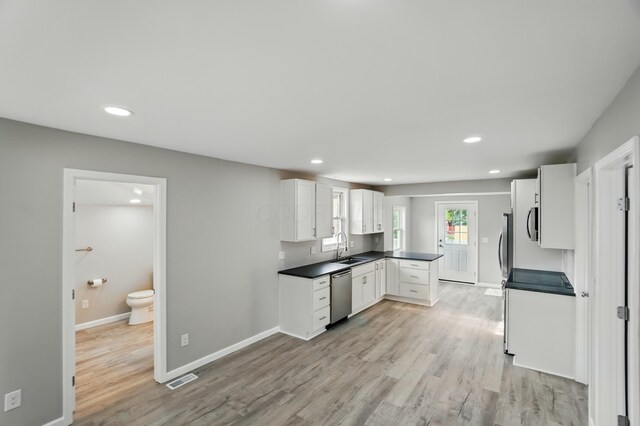 4881 Decker Ave NE, Thornville, OH 43076 - kitchen featuring stainless steel dishwasher, a sink, dark countertops, light wood-style floors, and white cabinets