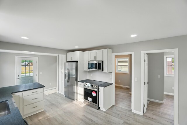 4881 Decker Ave NE, Thornville, OH 43076 - kitchen featuring stainless steel appliances, white cabinets, baseboards, dark countertops, and light wood finished floors