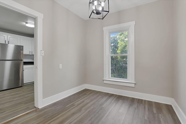 800 S Detroit St, Bellefontaine, OH 43311 - unfurnished dining area featuring wood finished floors, baseboards, and a chandelier