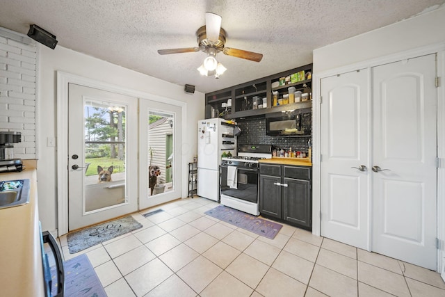 2107 Radnor Ave, Columbus, OH 43224 - kitchen featuring range with gas stovetop, freestanding refrigerator, black microwave, open shelves, and decorative backsplash