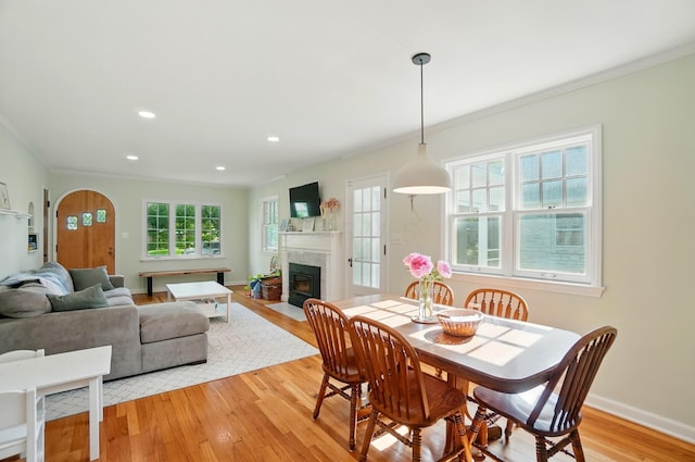 91 Nottingham Rd, Columbus, OH 43214 - dining area featuring a fireplace with flush hearth, ornamental molding, light wood-type flooring, arched walkways, and recessed lighting