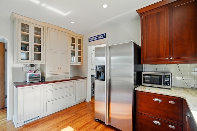 91 Nottingham Rd, Columbus, OH 43214 - kitchen featuring appliances with stainless steel finishes, light wood-style floors, decorative backsplash, glass insert cabinets, and recessed lighting