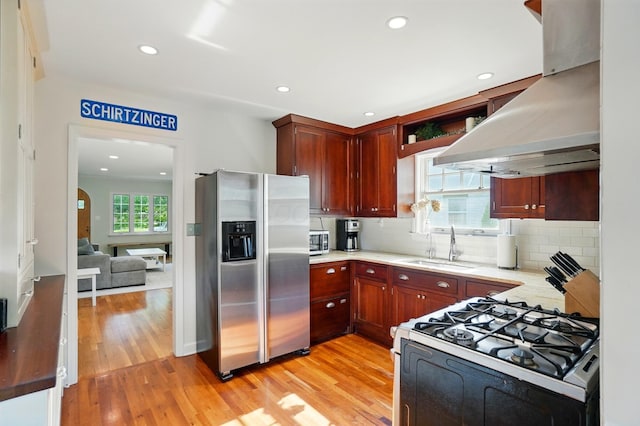 91 Nottingham Rd, Columbus, OH 43214 - kitchen featuring stainless steel fridge with ice dispenser, range with gas stovetop, exhaust hood, a sink, and light wood-style floors