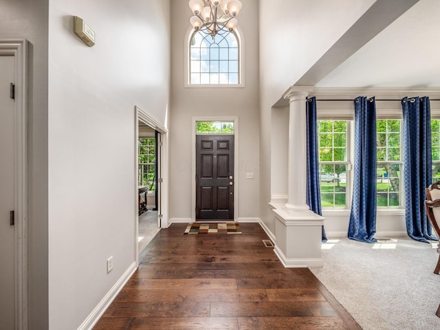 6810 Bearclover Dr, Dublin, OH 43016 - entrance foyer featuring plenty of natural light, ornate columns, dark wood-style floors, a chandelier, and a towering ceiling