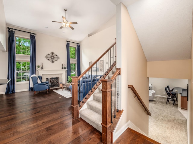 6810 Bearclover Dr, Dublin, OH 43016 - stairway with lofted ceiling, a ceiling fan, baseboards, a fireplace with flush hearth, and wood-type flooring