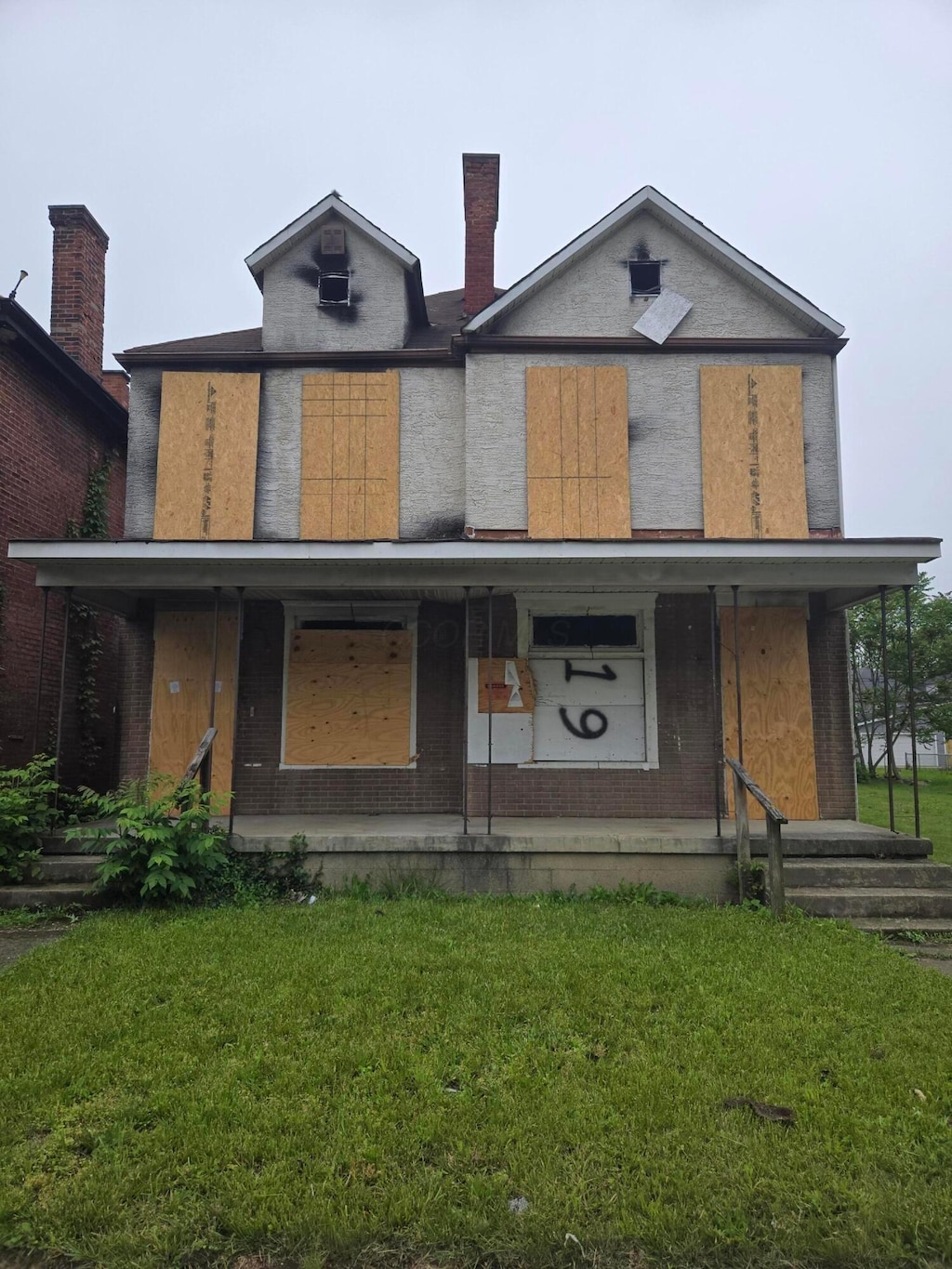 view of front of house with a porch, a front lawn, and brick siding