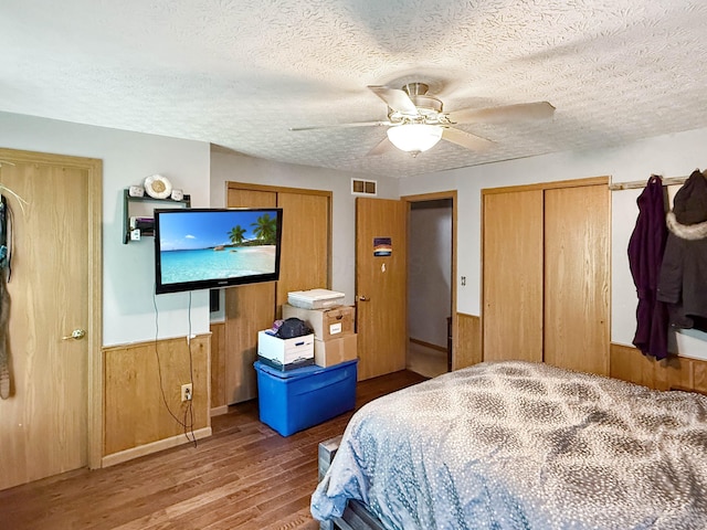 4890 Township Road 138 NW, Somerset, OH 43783 - bedroom featuring wood finished floors, wood walls, ceiling fan, two closets, and a textured ceiling