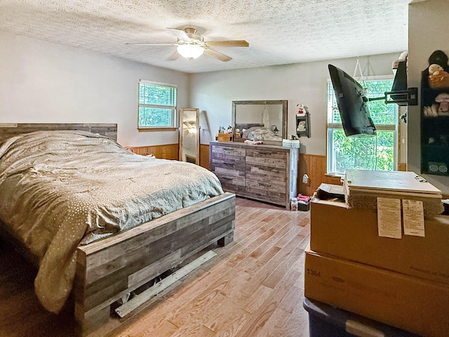 4890 Township Road 138 NW, Somerset, OH 43783 - bedroom featuring a wainscoted wall, light wood-style flooring, a textured ceiling, wooden walls, and ceiling fan