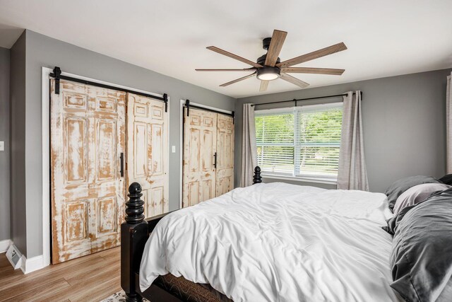 2174 Peachblow Rd, Lewis Center, OH 43035 - bedroom featuring a barn door, light wood finished floors, a ceiling fan, and baseboards