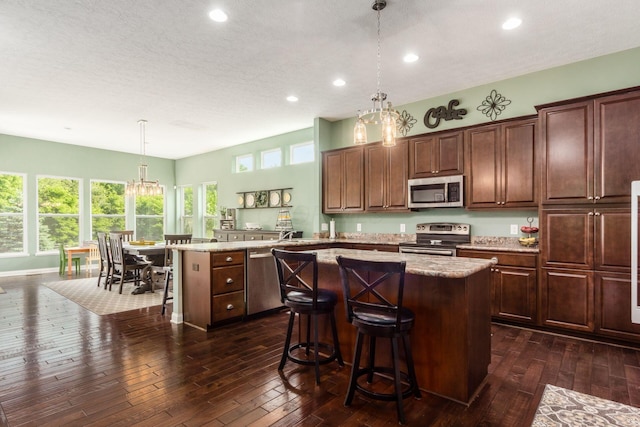 340 Olentangy W, Delaware, OH 43015 - kitchen featuring appliances with stainless steel finishes, a center island, a breakfast bar, dark wood-style flooring, and decorative light fixtures