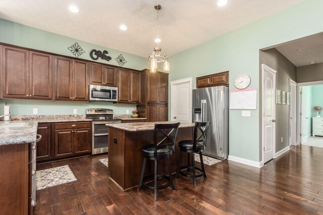 340 Olentangy W, Delaware, OH 43015 - kitchen with appliances with stainless steel finishes, a center island, dark wood-type flooring, light stone countertops, and a kitchen breakfast bar