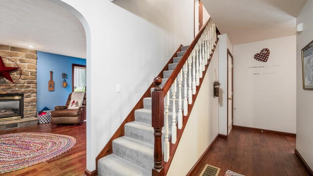 102 Sequoia Dr, Byesville, OH 43723 - stairs featuring hardwood / wood-style floors, arched walkways, a fireplace, and baseboards