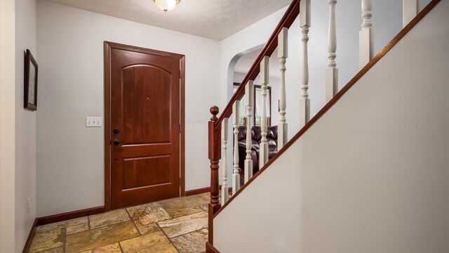 102 Sequoia Dr, Byesville, OH 43723 - entrance foyer with baseboards, stone tile flooring, stairs, arched walkways, and a textured ceiling