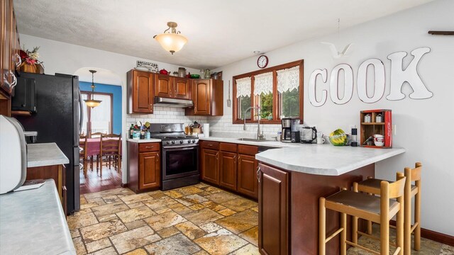 102 Sequoia Dr, Byesville, OH 43723 - kitchen featuring appliances with stainless steel finishes, under cabinet range hood, a peninsula, a sink, and a kitchen breakfast bar