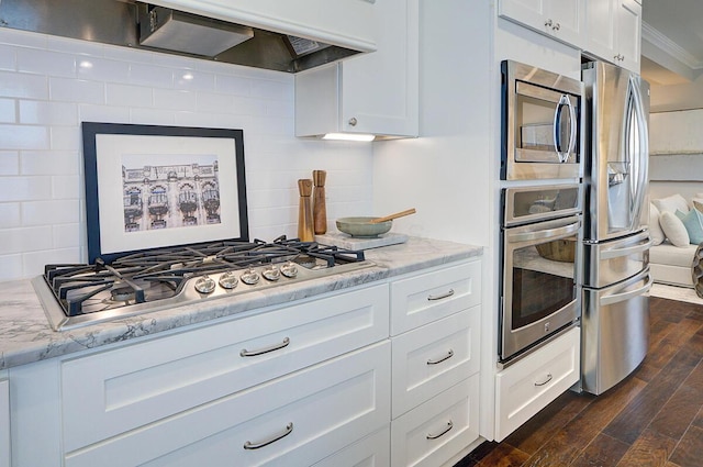 717 S 3rd St, Columbus, OH 43206 - kitchen featuring appliances with stainless steel finishes, extractor fan, dark wood-style flooring, white cabinets, and backsplash