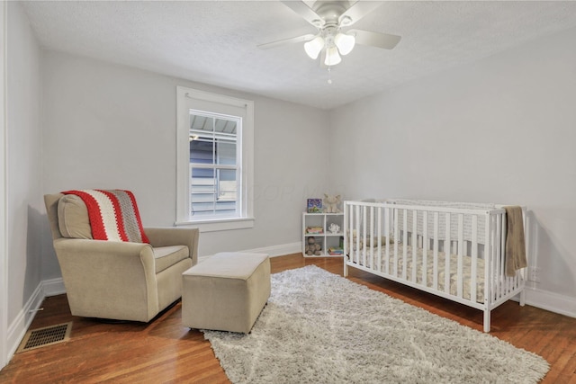 1442 S 4th St, Columbus, OH 43207 - bedroom featuring wood finished floors, a nursery area, baseboards, ceiling fan, and a textured ceiling