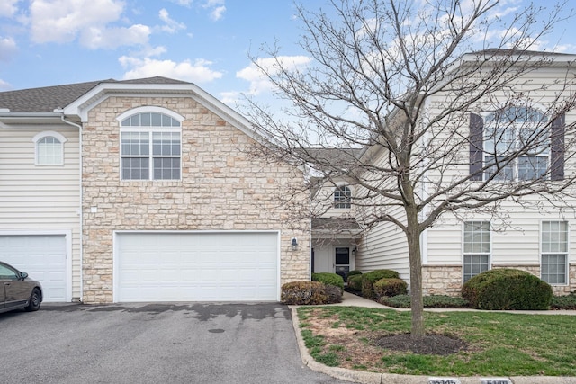 5145 Vinings Blvd Unit B, Dublin, OH 43016 - view of front of house with stone siding, driveway, an attached garage, and a shingled roof