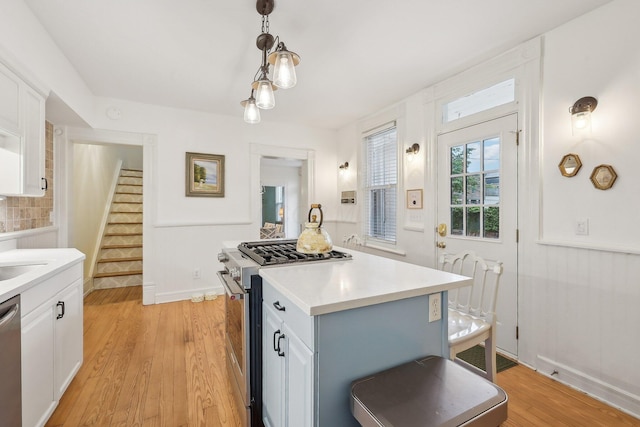 436 Beck St, Columbus, OH 43206 - kitchen featuring appliances with stainless steel finishes, white cabinetry, light countertops, light wood-style flooring, and hanging light fixtures