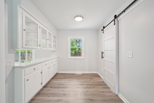 106 Woodrow Ave, Delaware, OH 43015 - kitchen with a barn door, light countertops, white cabinetry, light wood finished floors, and glass insert cabinets