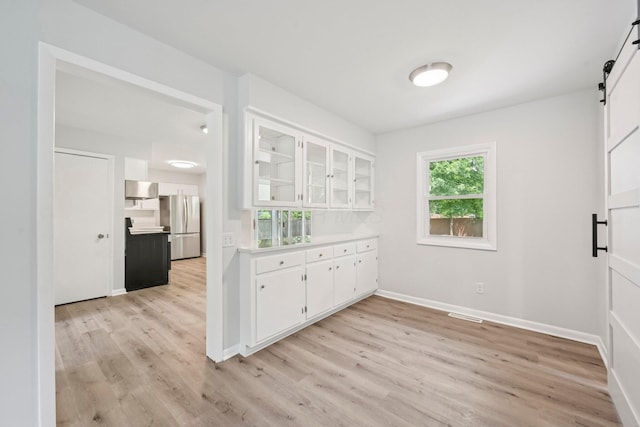 106 Woodrow Ave, Delaware, OH 43015 - kitchen with freestanding refrigerator, a barn door, light wood-style floors, and white cabinets