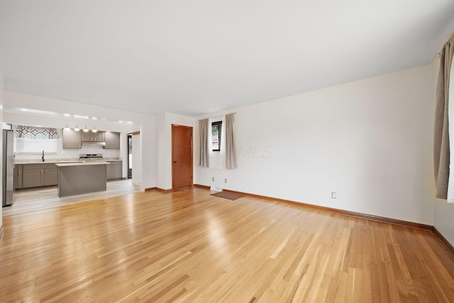 1345 Molly Ln, Columbus, OH 43207 - unfurnished living room featuring baseboards and light wood-style floors
