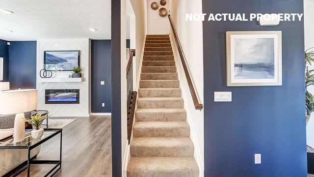 1444 Chrisman Dr, Columbus, OH 43223 - stairway with wood finished floors, baseboards, a large fireplace, and a textured ceiling