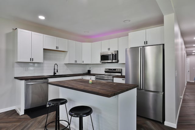 1208 Seymour Ave, Columbus, OH 43206 - kitchen featuring stainless steel appliances, wood counters, a sink, baseboards, and a breakfast bar area