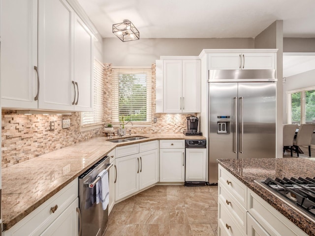 1488 Brittingham Ln, Powell, OH 43065 - kitchen with stainless steel appliances, white cabinetry, light stone countertops, and tasteful backsplash