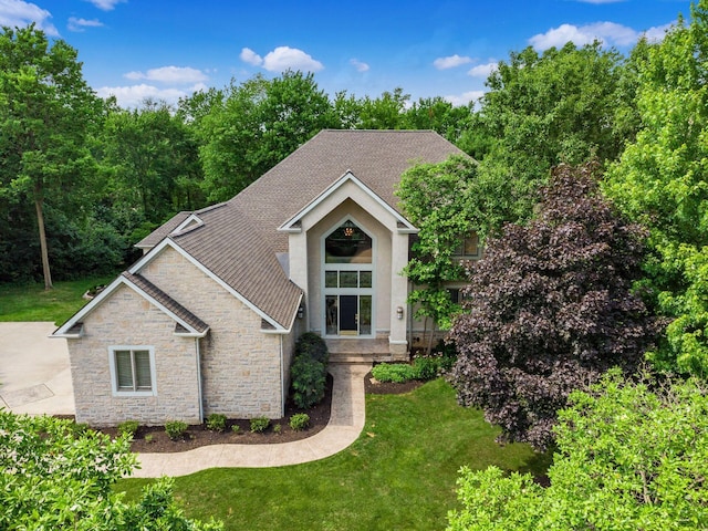 1488 Brittingham Ln, Powell, OH 43065 - view of front of home with stone siding, a front yard, a shingled roof, and stucco siding