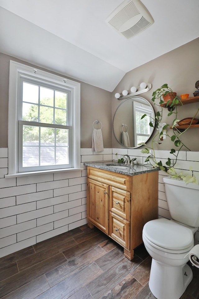 155 Aldrich Rd, Columbus, OH 43214 - bathroom with vanity, lofted ceiling, tile walls, plenty of natural light, and wainscoting
