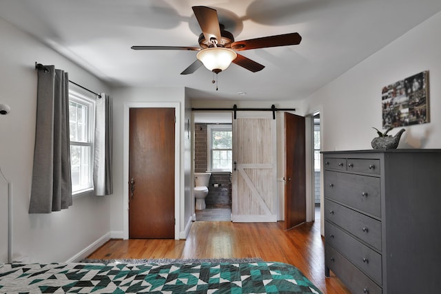 155 Aldrich Rd, Columbus, OH 43214 - bedroom with a barn door, light wood-type flooring, connected bathroom, and ceiling fan