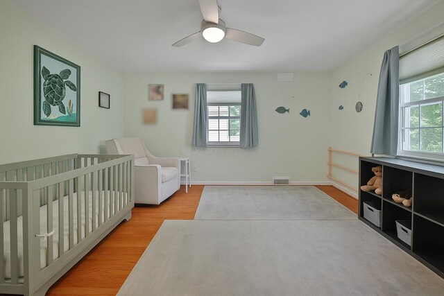155 Aldrich Rd, Columbus, OH 43214 - bedroom featuring multiple windows, wood finished floors, a ceiling fan, and a nursery area