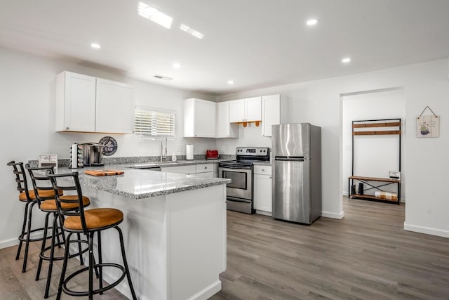 1997 Ferris Rd, Columbus, OH 43224 - kitchen with stainless steel appliances, a peninsula, wood finished floors, a kitchen breakfast bar, and white cabinets