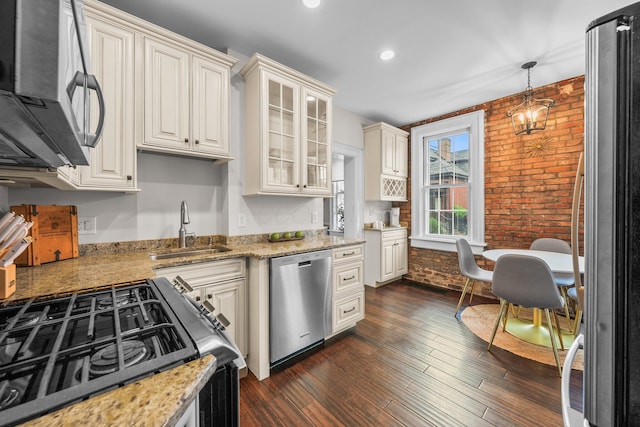 145 E Sycamore St, Columbus, OH 43206 - kitchen with appliances with stainless steel finishes, a sink, brick wall, light stone countertops, and glass insert cabinets