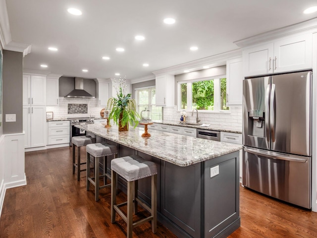 1360 Clubview Blvd S, Columbus, OH 43235 - kitchen featuring appliances with stainless steel finishes, wall chimney range hood, white cabinets, backsplash, and a center island