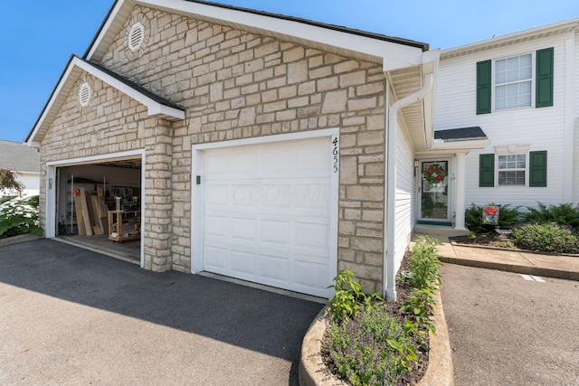 4655 Athalia Dr Unit 20B, Columbus, OH 43228 - view of front of home featuring stone siding, a garage, and driveway