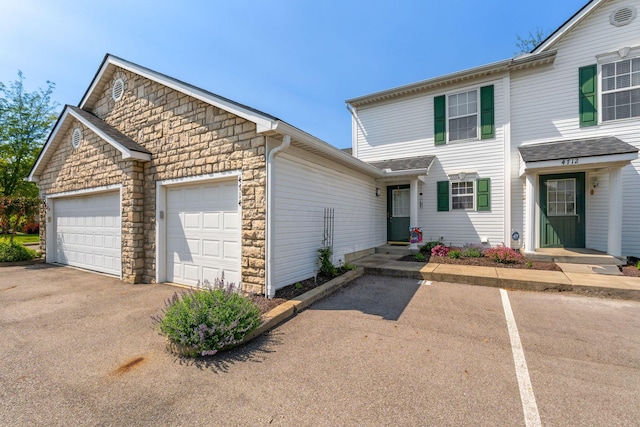 4714 Athalia Dr Unit 26B, Columbus, OH 43228 - view of front of property featuring stone siding, a garage, and asphalt driveway