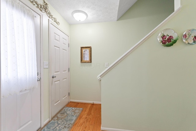 4714 Athalia Dr Unit 26B, Columbus, OH 43228 - foyer featuring light wood finished floors, stairway, baseboards, and a textured ceiling